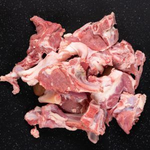 Fresh Raw Goat Meat Stew Like Cuts On Black Cutting Board.