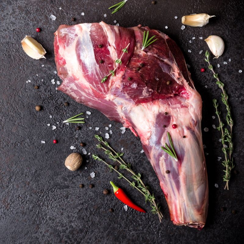 Raw Fresh Lamb Meat Shank And Seasonings On Black Stone Background.