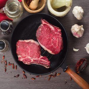 Raw Fresh Meat Rib Eye Steak Composition In Grill Pan On A Wooden Background