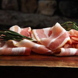 Raw Sliced Bacon With Thyme Leaves Ready For Cooking.