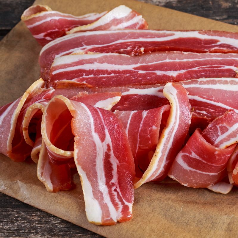 Raw Smoked Streaky Sliced Bacon On Crumpled Paper.