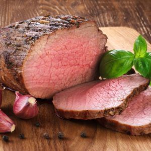 Baked Meat, Garlic And Basil On A Wooden Background. Roast Beef.